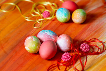 Colored eggs for Easter on the table next to the decoration of colored ribbons.