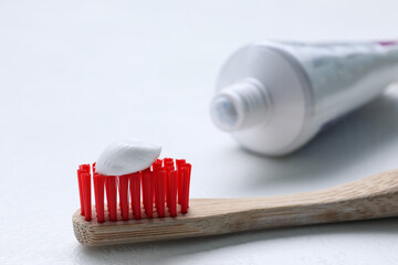 Brush with toothpaste and tube on white background, closeup