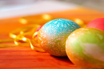 Colored eggs for Easter on the table next to the decoration of colored ribbons.