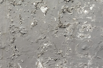 Old peeling gray paint on the stuccoed wall. As a natural background and texture.