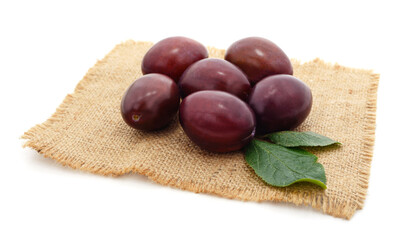 Blue plums with leaves on burlap.
