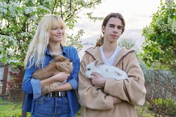 Teenagers with rabbits in their hands, pets a couple of decorative rabbits