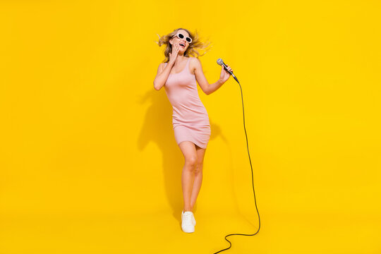 Full length body size view of pretty trendy cheerful amazed wavy-haired girl singing having fun isolated over bright yellow color background