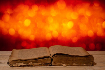 an old open book lies on a wooden table against a bokeh background