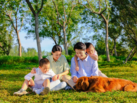 Happy family of four and pet dog playing in the park