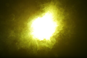 Artificial magic yellow light illuminates smoke on dark background