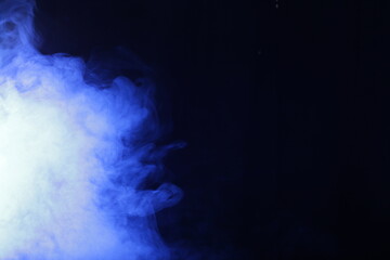 Obraz na płótnie Canvas Artificial smoke in blue light on black background