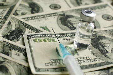 Vaccine vial and syringe on the background of one hundred dollar