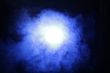 Artificial magic smoke in blue light on black background