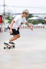Fototapeta premium Asian young man playing surfskate or skate board in gas station urban city outdoor. Extream sports