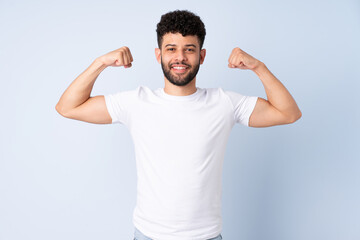 Young Moroccan man isolated on blue background doing strong gesture