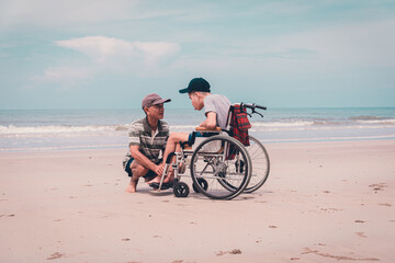 Asian special child on wheelchair on the beach with parents in family holiday to travel, exercise and learning about nature around the sea beach, Life in the education age, Happy disabled kid concept.