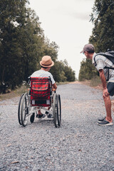 Disabled child sitting on wheel​chair​ and father have fun with activity on the outdoor park on travel, Lifestyle in education age of disabled children, Happy disability kid concept.