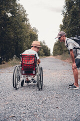 Naklejka premium Disabled child sitting on wheel​chair​ and father have fun with activity on the outdoor park on travel, Lifestyle in education age of disabled children, Happy disability kid concept.