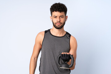 Young Moroccan man isolated on blue background making weightlifting with kettlebell