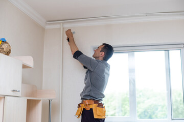 Man collects cornice for curtains © Angelov