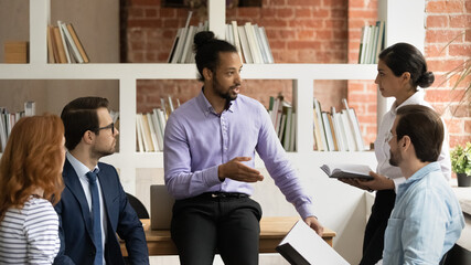 Concentrated young serious african american boss mentor leading brainstorming meeting with...