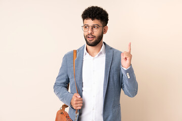 Young business Moroccan man isolated on beige background thinking an idea pointing the finger up