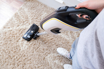 cordless vacuum cleaner is used to clean the carpet in the room. Housework with a new handheld...