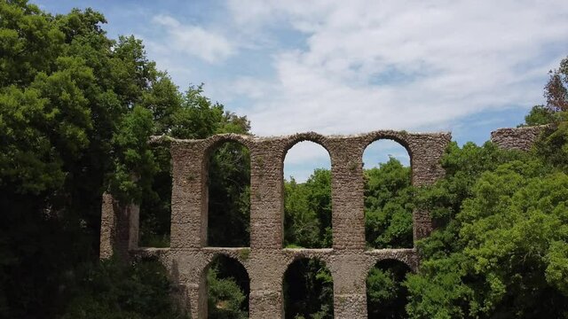 Europe, Italy, Lazio , Monterano - drone aerial view of ancient ruin town of Monterano vecchia - aqueduct and ruins of the old town - drone passes through an ancient Roman aqueduct