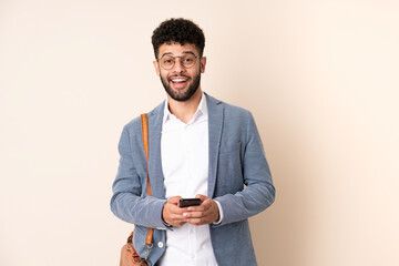 Young business Moroccan man isolated on beige background surprised and sending a message