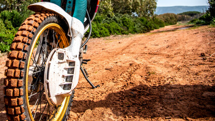 Front wheel of an adventure bike on a dirt road with mud