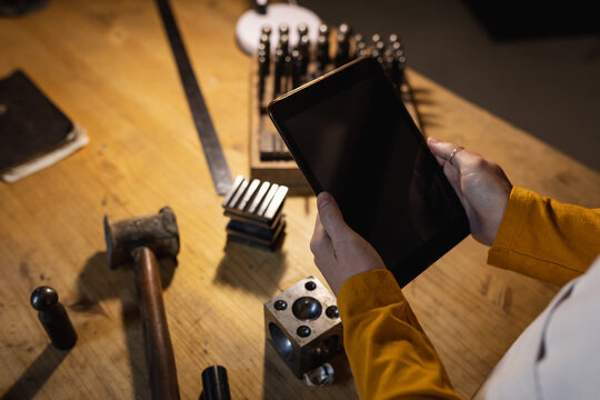 Close up of hands of caucasian female jeweller holding tablet with copy space on screen - Powered by Adobe