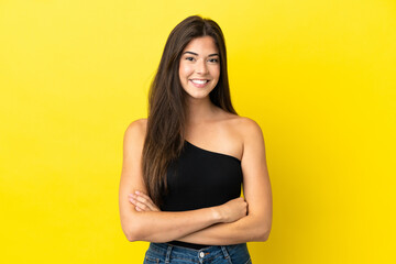 Young Brazilian woman isolated on yellow background keeping the arms crossed in frontal position
