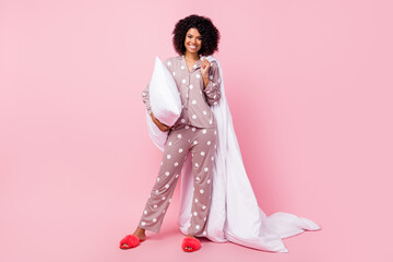 Photo of funny pretty wavy dark skin lady dotted sleepwear dancing holding white blanket pillow isolated pink color background