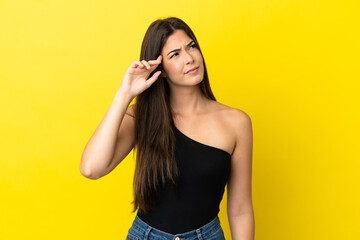 Young Brazilian woman isolated on yellow background making the gesture of madness putting finger on...