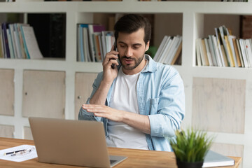 Professional skilled young lawyer financial advisor giving consultation to client by phone call, working in modern office. Concentrated 30s millennial manager discussing project ideas distantly.