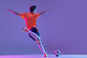 One male soccer football player in action and motion isolated on gradient lilac pink background in...