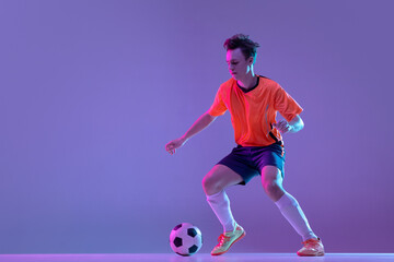 One male soccer football player in action and motion isolated on gradient lilac pink background in...