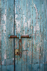 Old and rusty bolt and lock on exterior door with blue paint