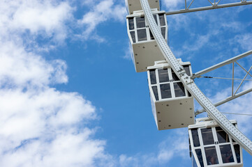Fototapeta na wymiar Ferris wheel cabins in a sunny day with white clouds