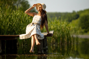 Relaxing young woman on wooden pier at the lake