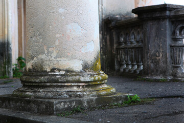 Architectural columns with traces of destruction and overgrown with moss. Mold and moss on old, abandoned architectural columns. Abandoned architectural structures. Decline and neglect. Copy space
