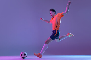 Fototapeta na wymiar One male soccer football player in action and motion isolated on gradient lilac pink background in neon light