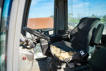 Old empty shabby driver's seat in the cab of a tractor, crane or other agricultural or construction...