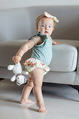 little caucasian baby girl ten months old playing with stuffed teddy bear toy at home or nursery....