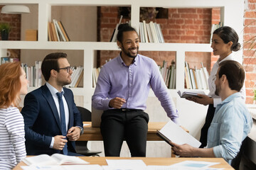 Smiling handsome young african american businessman holding negotiations brainstorming meeting with...
