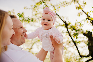 mom, dad and daughter in spring flowering garden. cleft lip in infants.