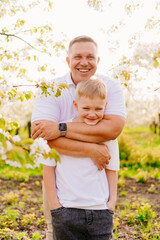 dad and son teenager in a flowering spring cherry orchard.
