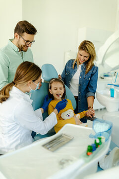 Female doctor with instruments in the hands looking girls teeth.