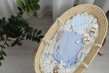 Fototapeta na wymiar Cute baby clothes and accessories in basket bassinet at home, top view
