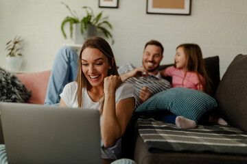 Mother sits on the floor and celebrates the good news at work, while the father and daughter cuddle.