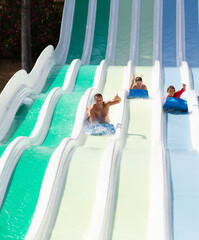 father and kids having fun sliding in water park