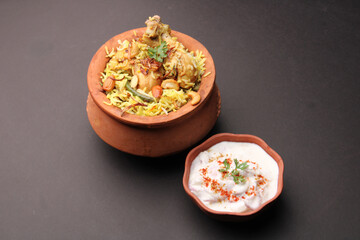  Spicy chicken dum biryani in traditional handi or clay pot. served with onion raita