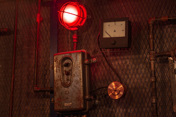 Old iron industrial amperemeter with the red warning bulb.