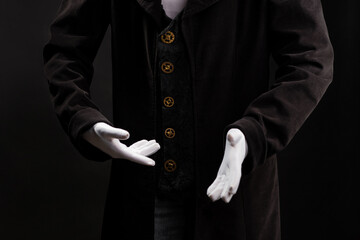 Hand gestures. Showman or magician illusionist in white gloves on a black background.